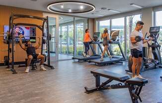 A man is working out on a machine in a gym with other people exercising in the background.at Icon One, Florida, 32114