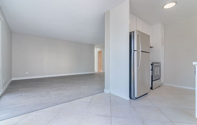 an empty kitchen and living room with a refrigerator at Citra Apartments LLC, San Diego