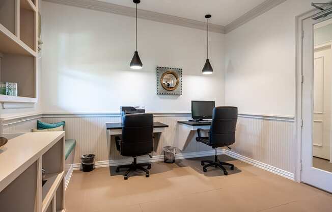 Resident business center with computers and a bookshelf and sitting area