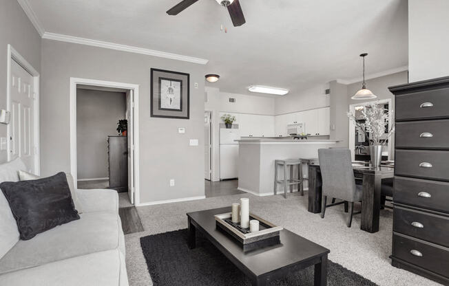 a black and white photo of a living room with a kitchen in the background