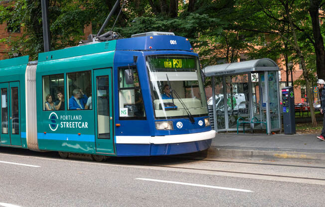 a blue tram is stopped at a bus stop