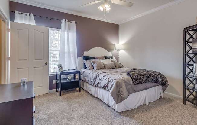 A bedroom with a bed, nightstand, and a ceiling fan.