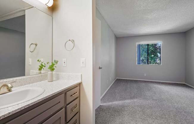 a bathroom with a sink and a mirror and an empty room