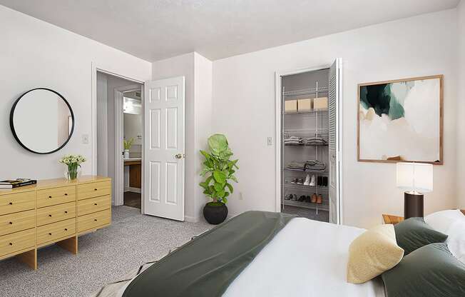 A bedroom with a bed, dresser, and a walk-in closet with organizers at Brentwood Park Apartments in LaVista, NE