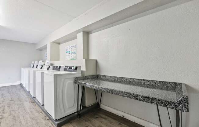 A laundry room with a washer and dryer on the left and a bench on the right.