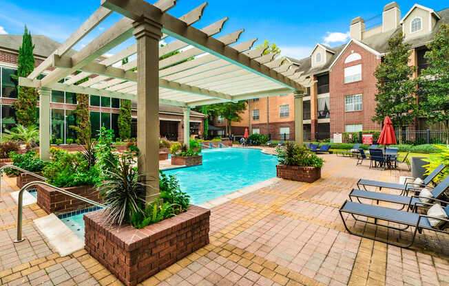 A pool area with a pergola and lounge chairs.
