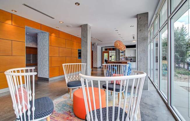 A room with a white table and chairs with orange and black cushions.