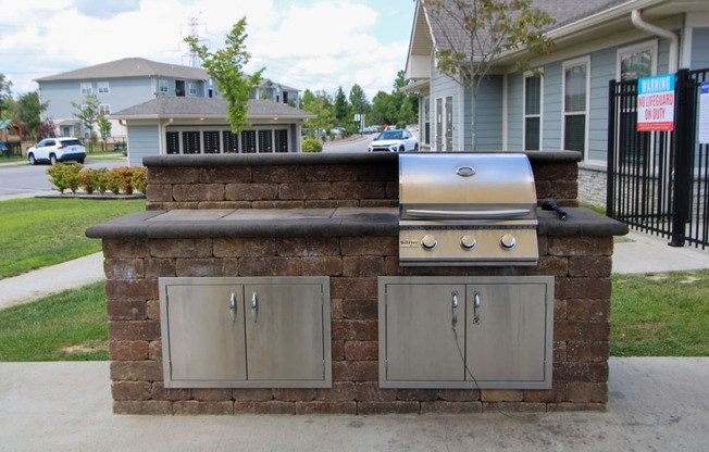 a brick bar with a grill and cabinets in front of a house