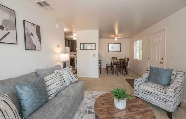 A living room with a grey couch, a wooden coffee table, and a striped armchair.