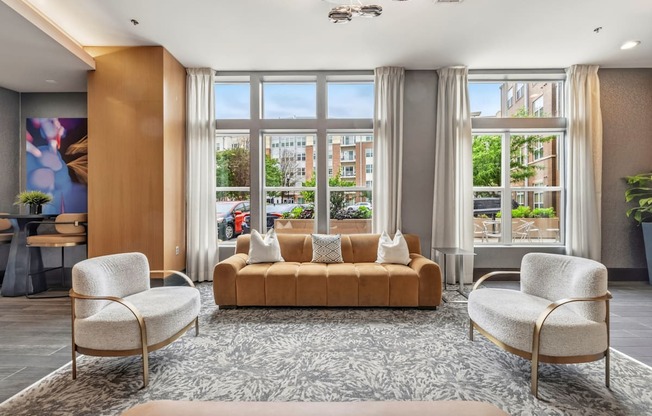 A living room with a sofa, two chairs and a rug.
