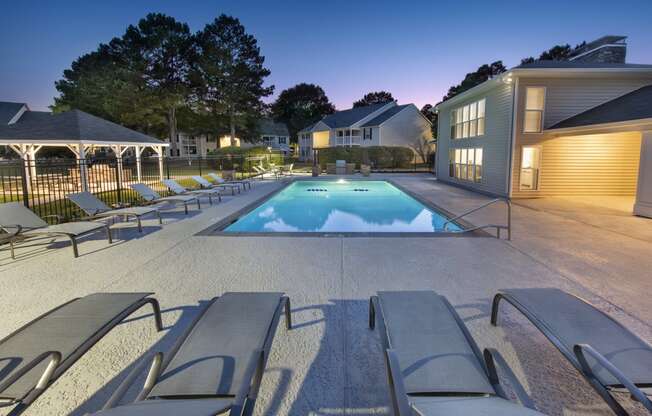 a swimming pool with lounge chairs around it at night
