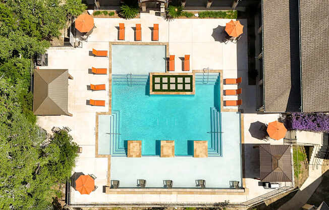 An aerial view of a pool surrounded by orange chairs and green plants.