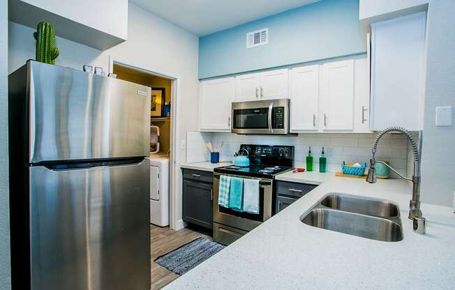 A kitchen with a stainless steel refrigerator and a sink.