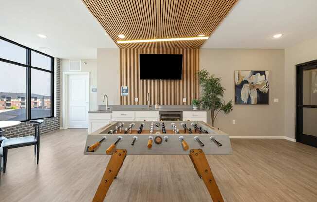 A foosball table in the middle of a room with a tv mounted on the wall.