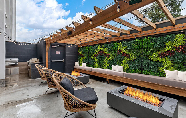 a patio with a fire pit and a green wall