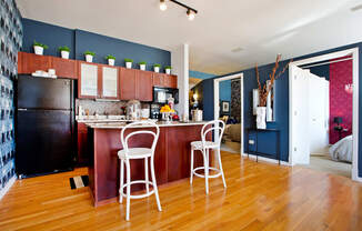 a kitchen and living room with a bar and a refrigerator