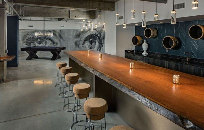 a long bar with stools in a room with a pool table