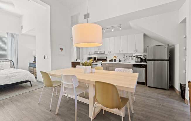 a dining room with a wooden table and chairs and a kitchen with stainless steel appliances