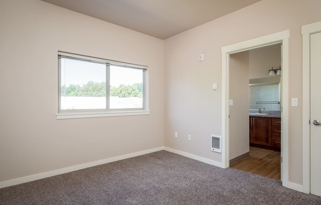 a bedroom with a large window and carpet