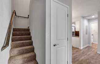 the landing of a staircase in a home with a door to a hallway and a