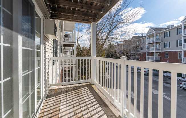 a porch with a white railing and a building in the background