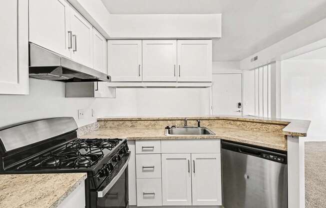 A kitchen with stainless steel appliances and white shaker-style cabinets at Trappers Cove Apartments, Lansing
