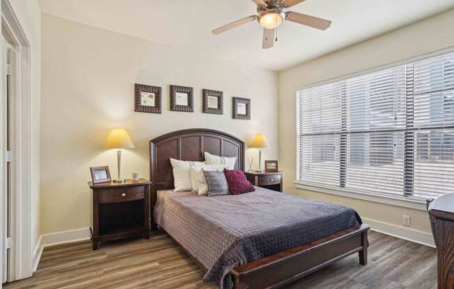 A bedroom with a bed, nightstands, and a ceiling fan.