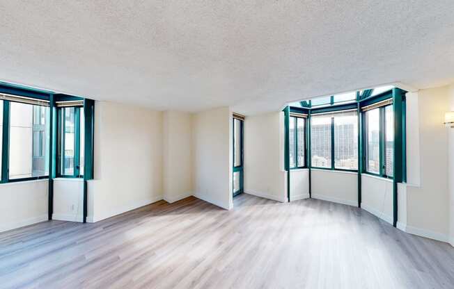 an empty living room with hardwood floors and large windows