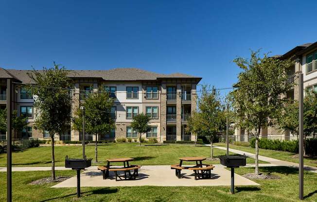 A modern building with a grassy area in front and two picnic tables.