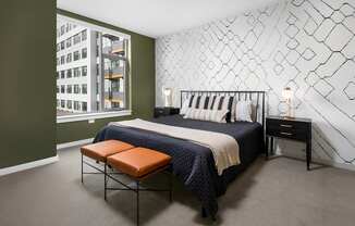 A bedroom with a bed, bench, and wall decoration.