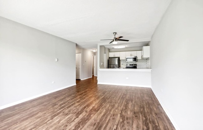 an empty living room and kitchen with a ceiling fan