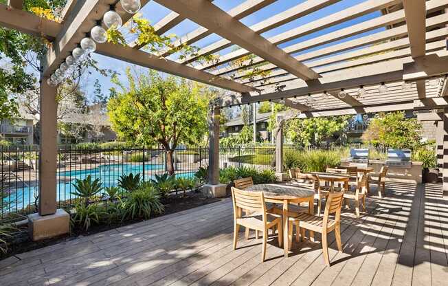 A wooden deck with a table and chairs overlooking a pool.