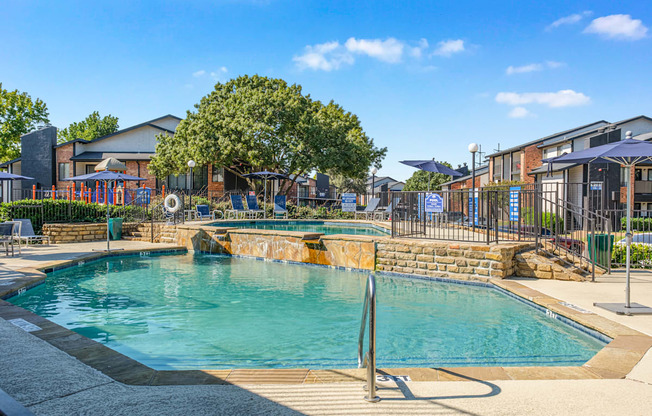 A large outdoor swimming pool surrounded by a fence and trees.