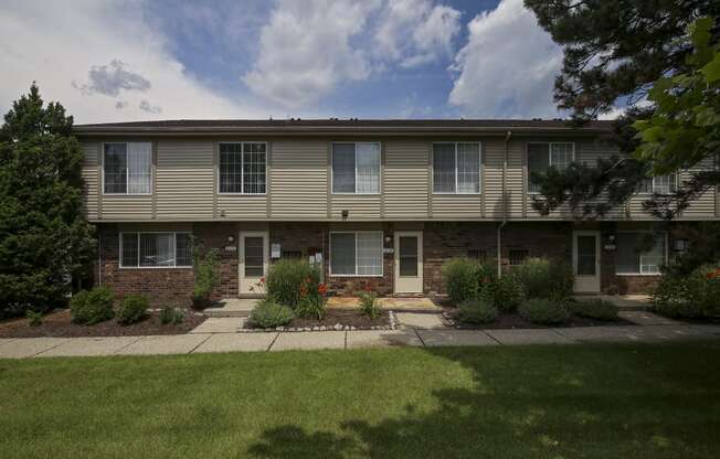 an apartment building with a lawn and plants in front of it at Village Club of Rochester Hills, Shelby Township