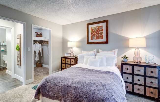 A bedroom with a bed, nightstands, and a painting on the wall.