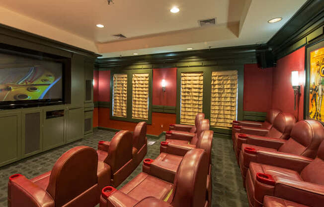 a screening room with red leather chairs and a television