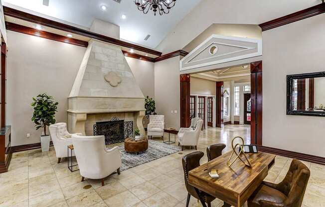 A large, elegant room with a fireplace and a dining table set for six.