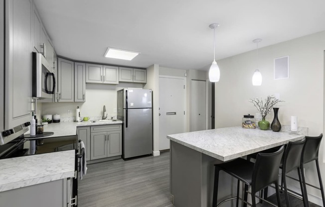 an open kitchen with a large island, plank flooring, and stainless steel appliances at Willows Court Apartment Homes, Seattle