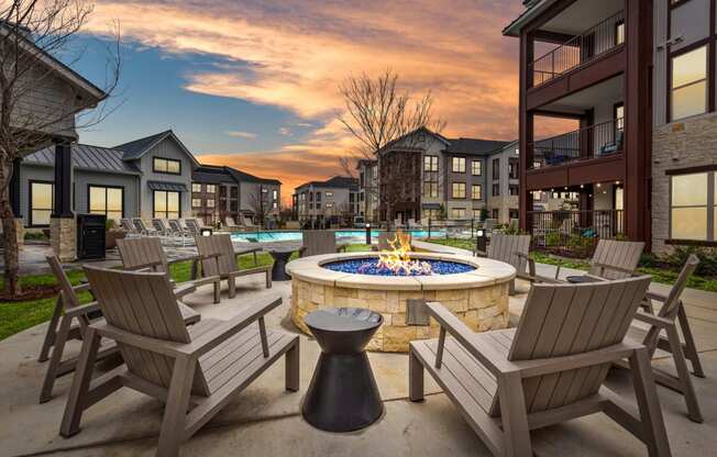 an outdoor patio with a fire pit and chairs at dusk