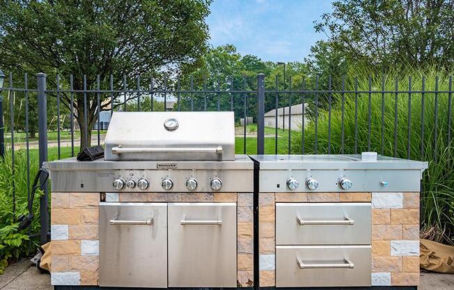 Two stone BBQs with a grill on top and a smaller one on the right.