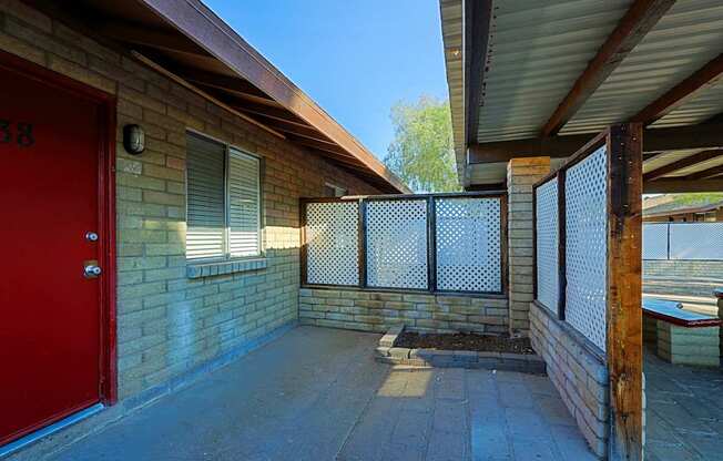 A red door is on the left side of a brick building.