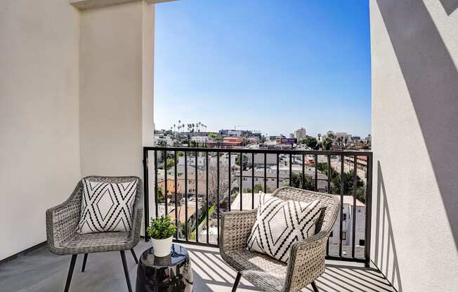 a balcony with two chairs and a view of the city