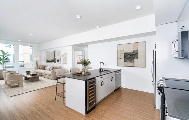 Open-concept kitchen with a center island, built-in wine cooler, and seamless flow into a bright living area filled with natural light