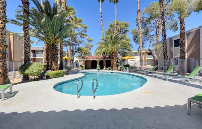A pool surrounded by palm trees and lounge chairs.