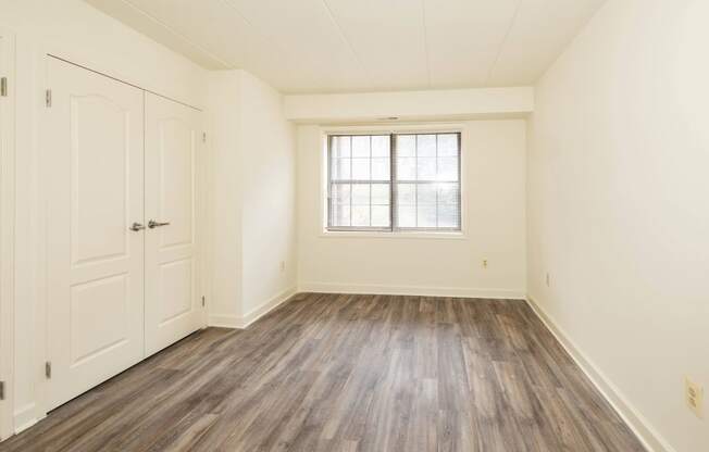 a bedroom with hardwood floors and white walls