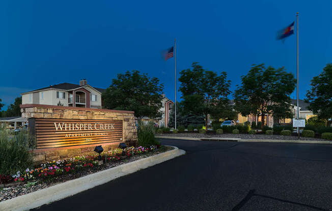 A sign that reads "Whisper Creek" is in front of a building.