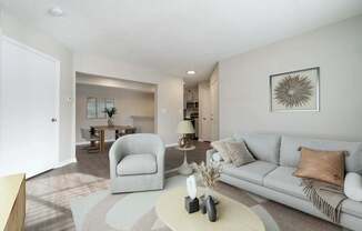 A living room with a grey couch, a white coffee table, and a grey armchair.