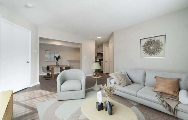A living room with a grey couch, a white coffee table, and a grey armchair.