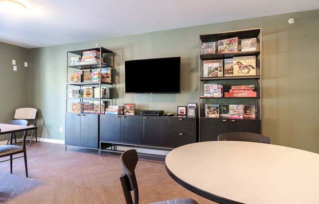 A room with a table, chairs, and a bookshelf filled with books.