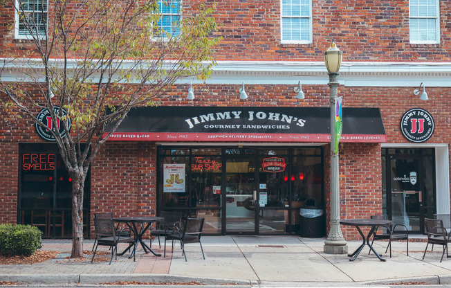 the front of a restaurant with a black awning and tables and chairs